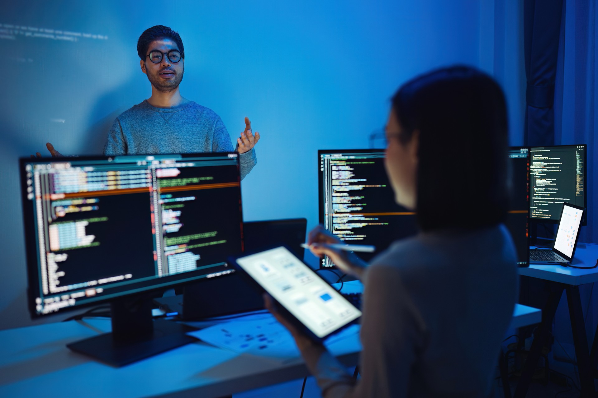 Indian man developer presentation about coding software data with devops team at night in office